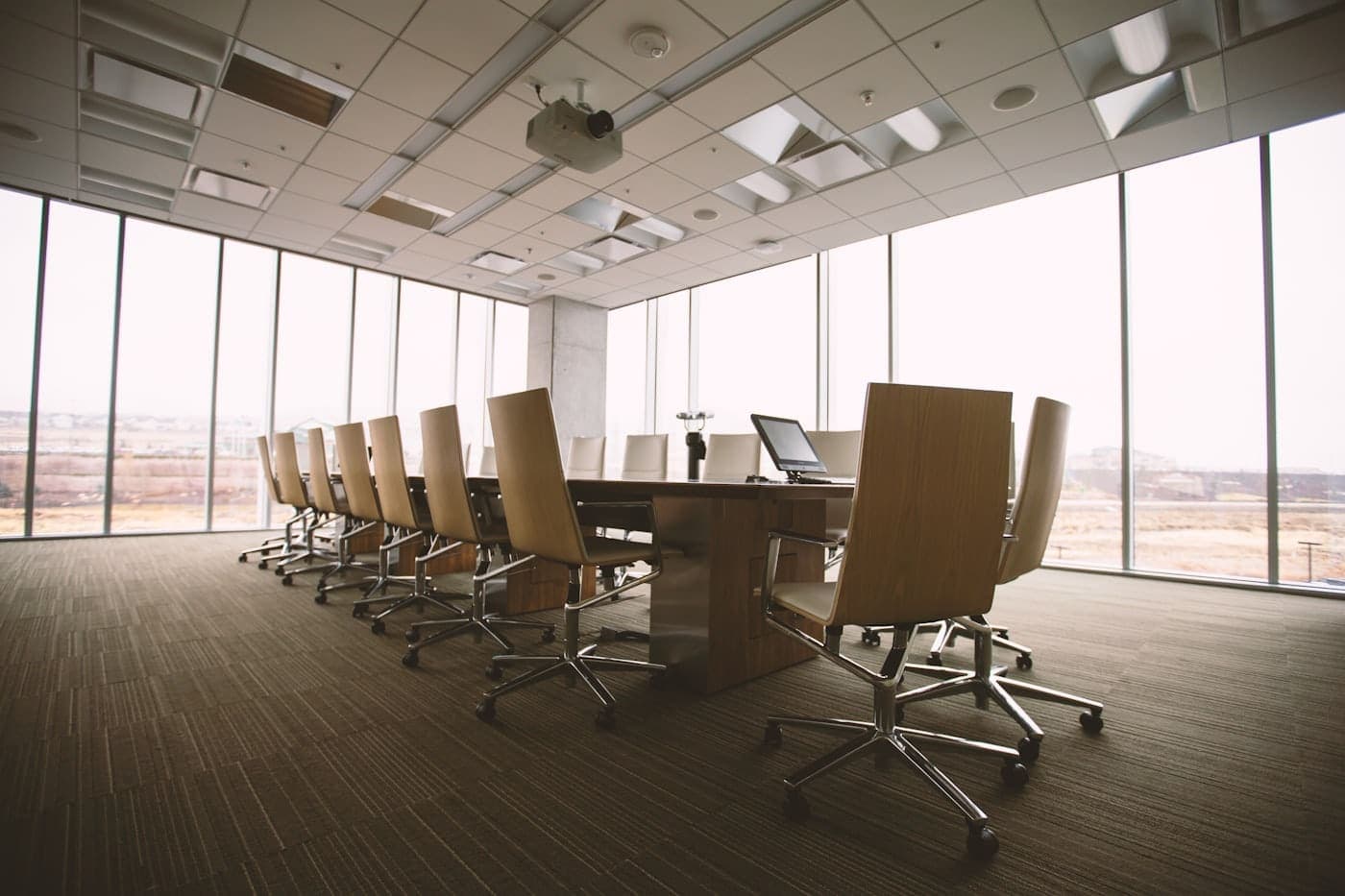 Empty oval brown wooden conference table and chairs inside a conference room