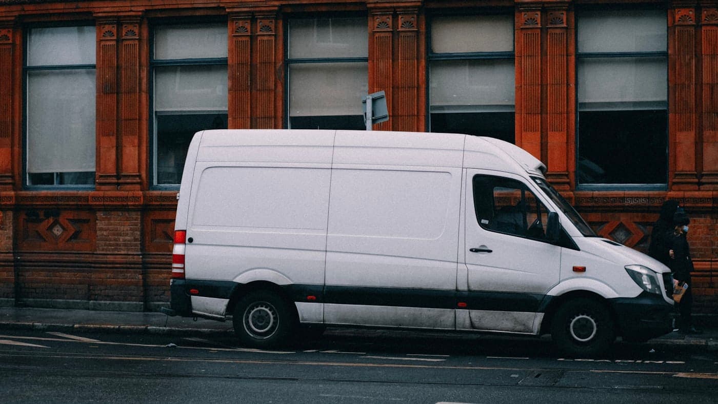 White delivery van parked along the side of a quiet street