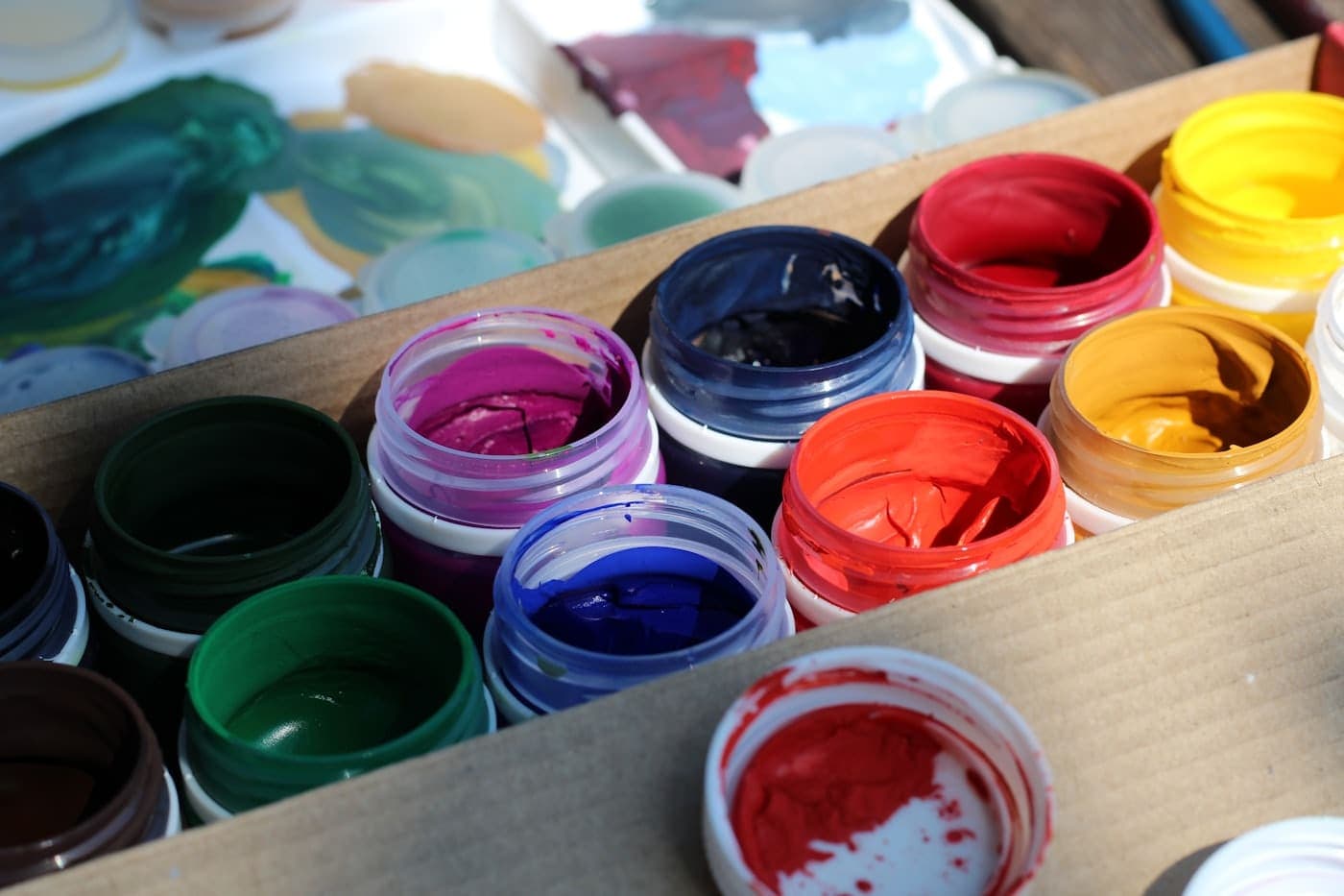 Open box filled with rows of paint tubes in many colours