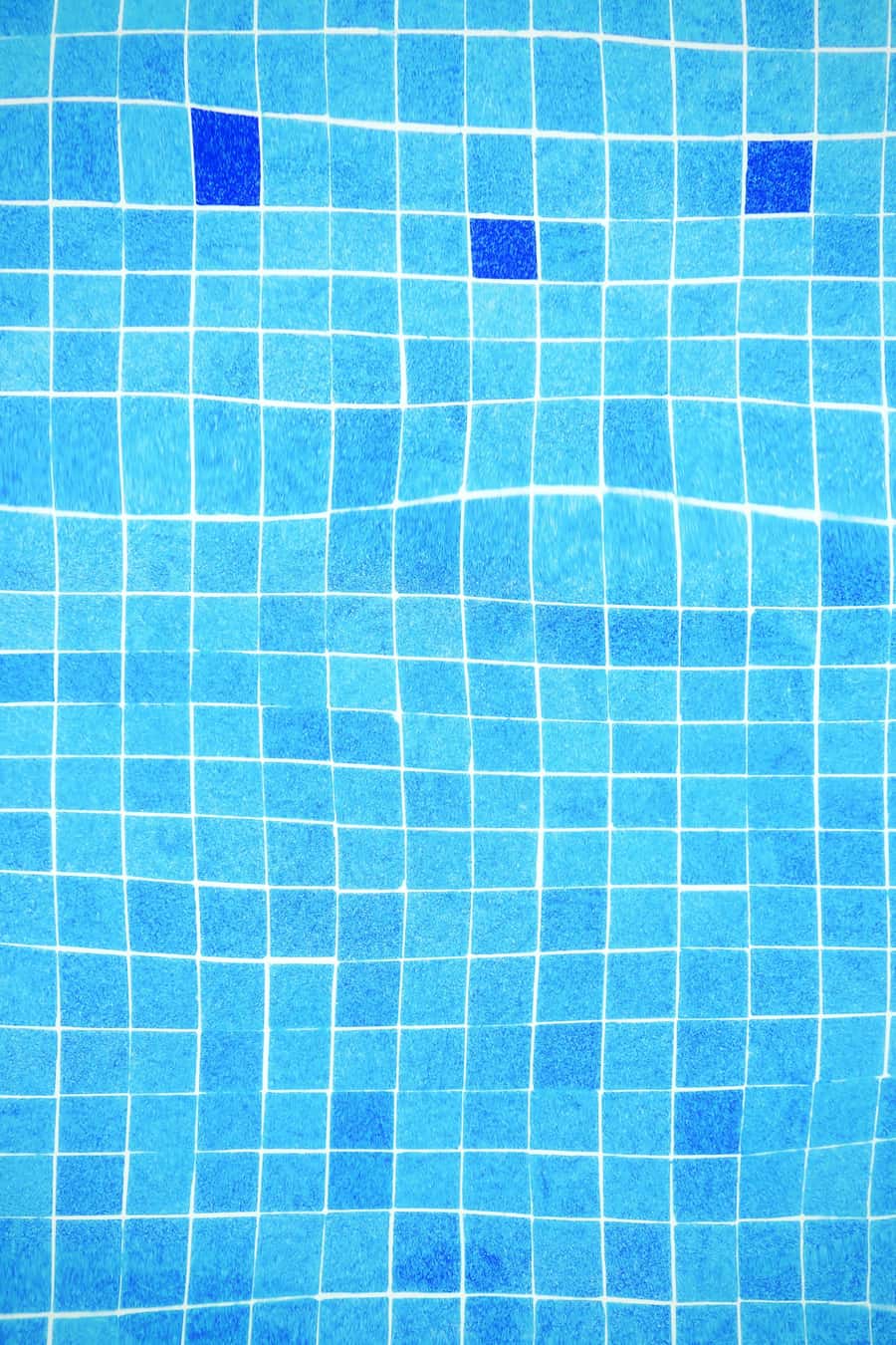 Blue tiled swimming pool with sunlight reflecting off the tile edge